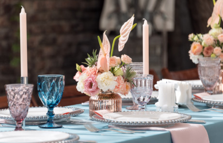 Festlich gedeckter Tisch mit Kerzen, bunten Weingläsern, Blumen und Tischdecke
